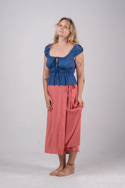 Woman wearing a blue top and pink skirt on a white background