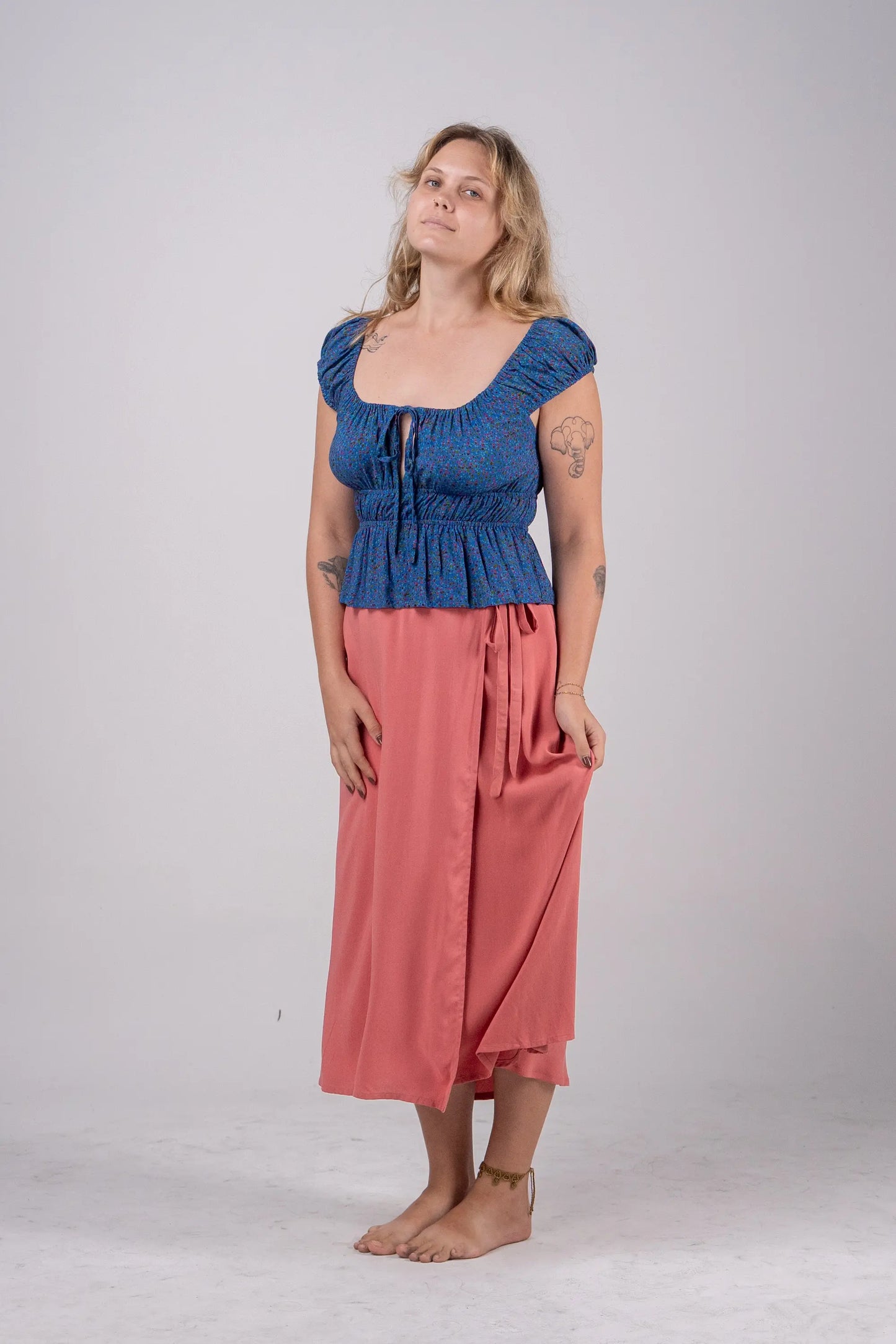 Woman wearing a blue top and pink skirt on a white background