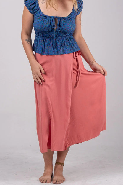 Woman wearing a blue top and pink skirt on a white background