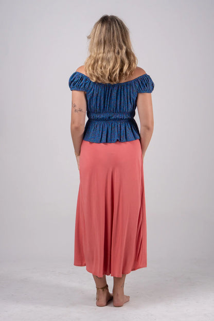 Woman wearing a blue top and pink skirt on a white background