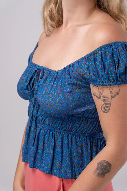 Blue floral off-shoulder top worn by a person on a plain background