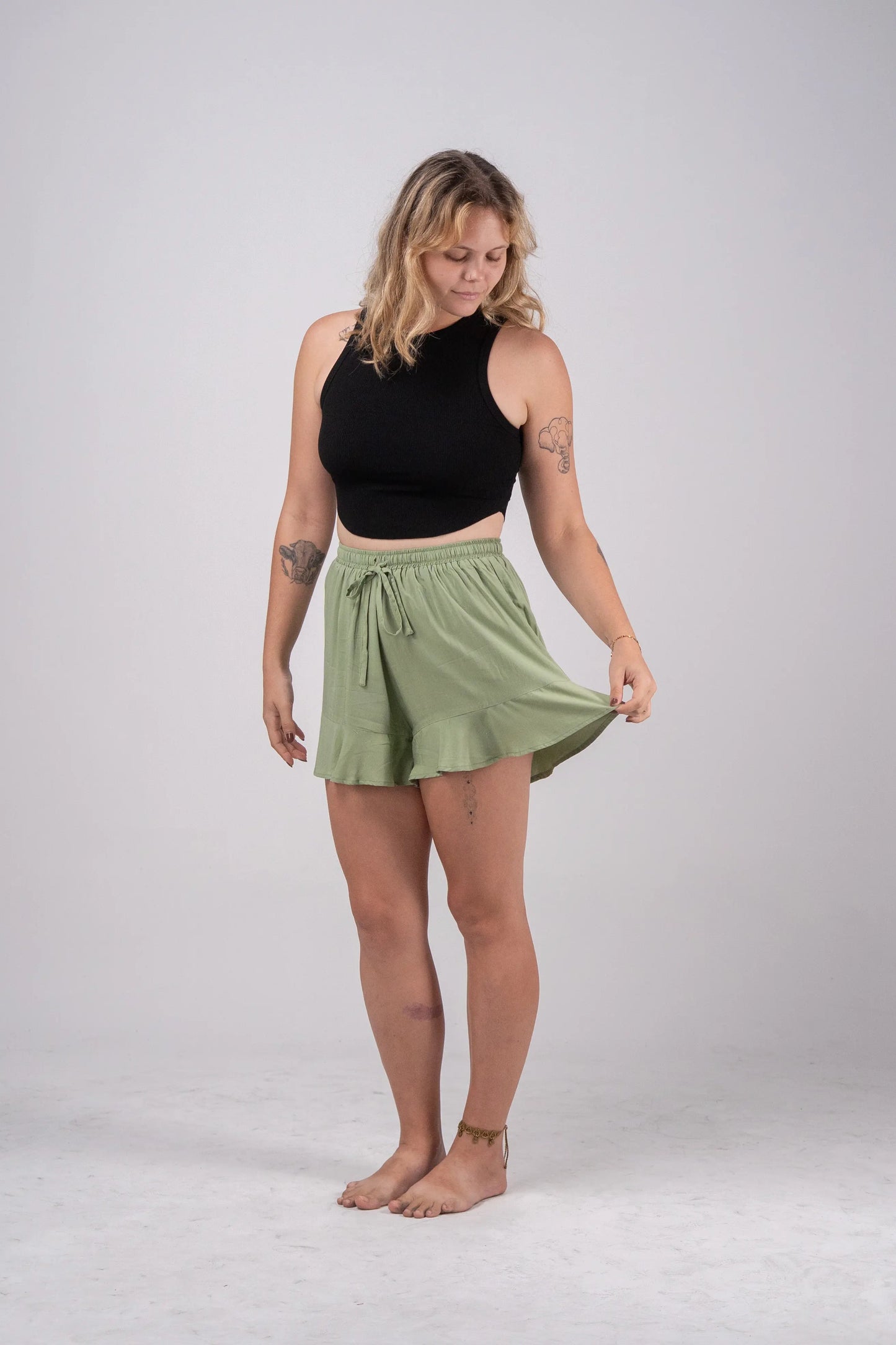 Woman wearing a black sleeveless top and green skirt on a white background