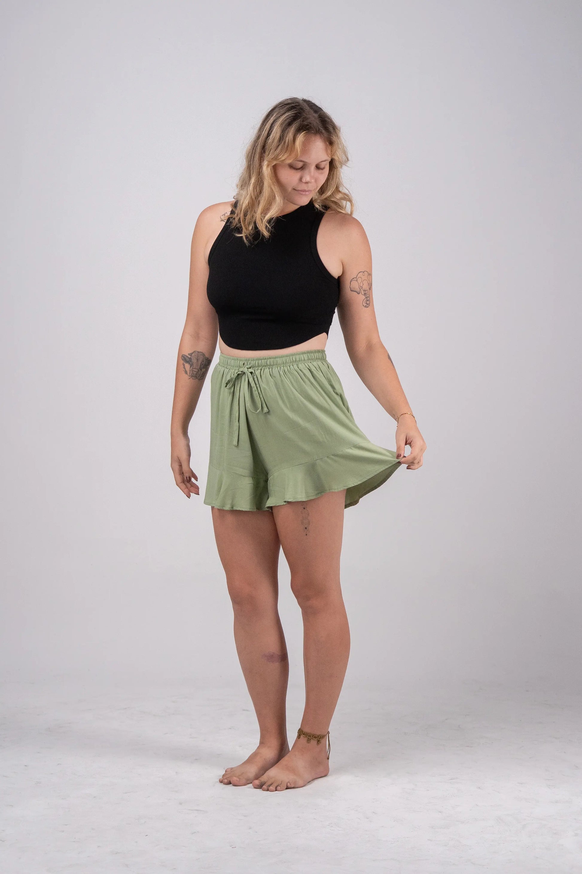 Woman wearing a black sleeveless top and green skirt on a white background