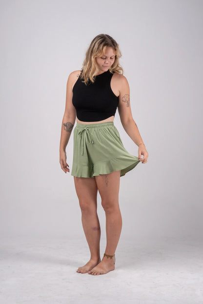 Woman wearing a black sleeveless top and green skirt on a white background