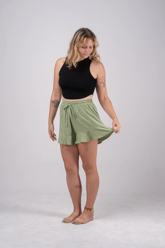 Woman wearing a black sleeveless top and green skirt on a white background