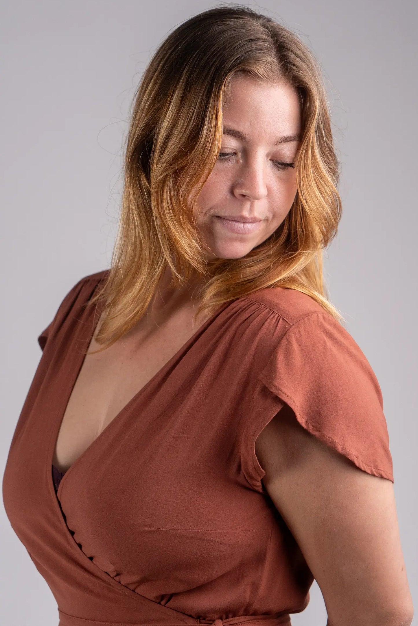 Woman wearing a rust-colored dress against a gray background