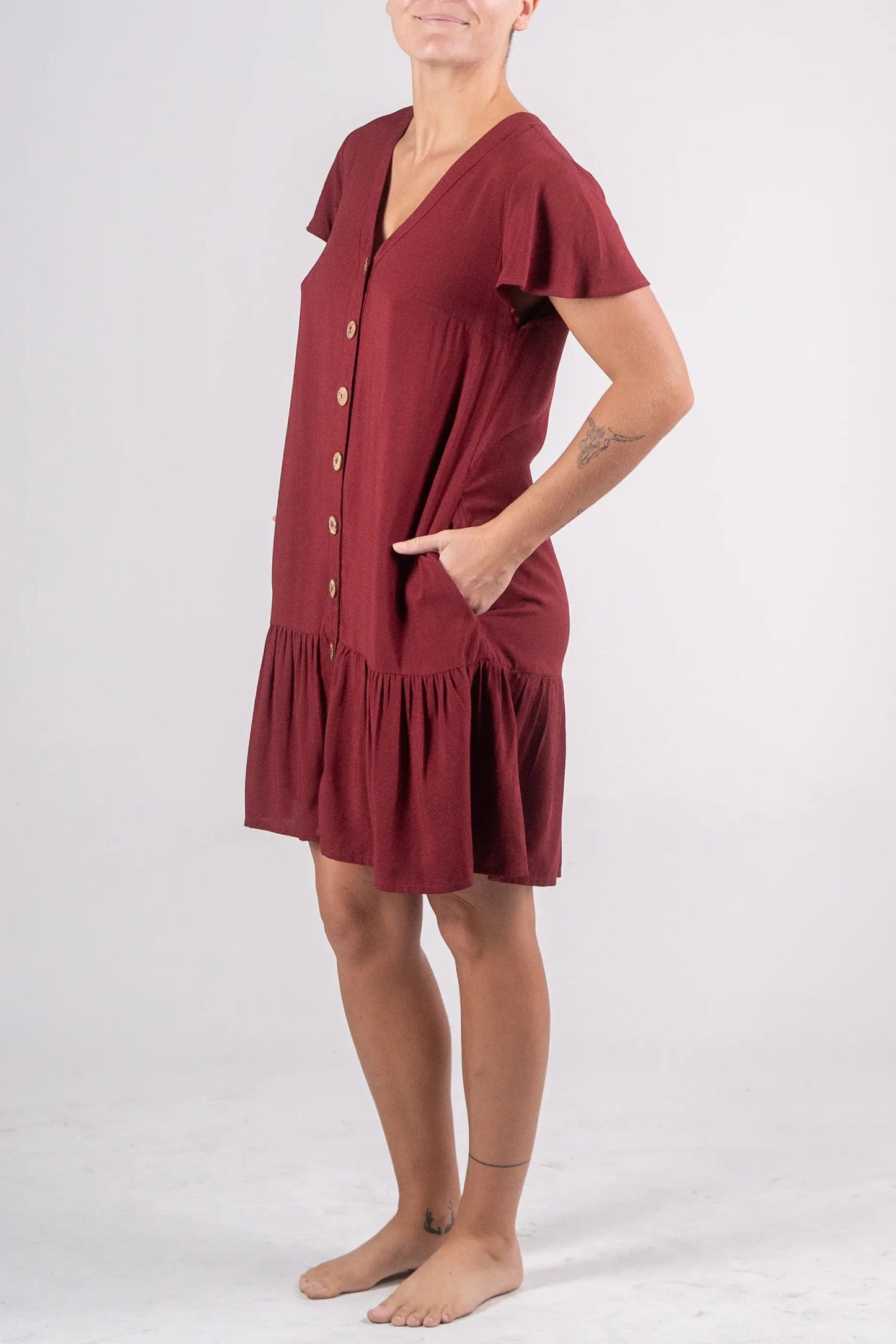 Woman wearing a burgundy dress with buttons on a white background