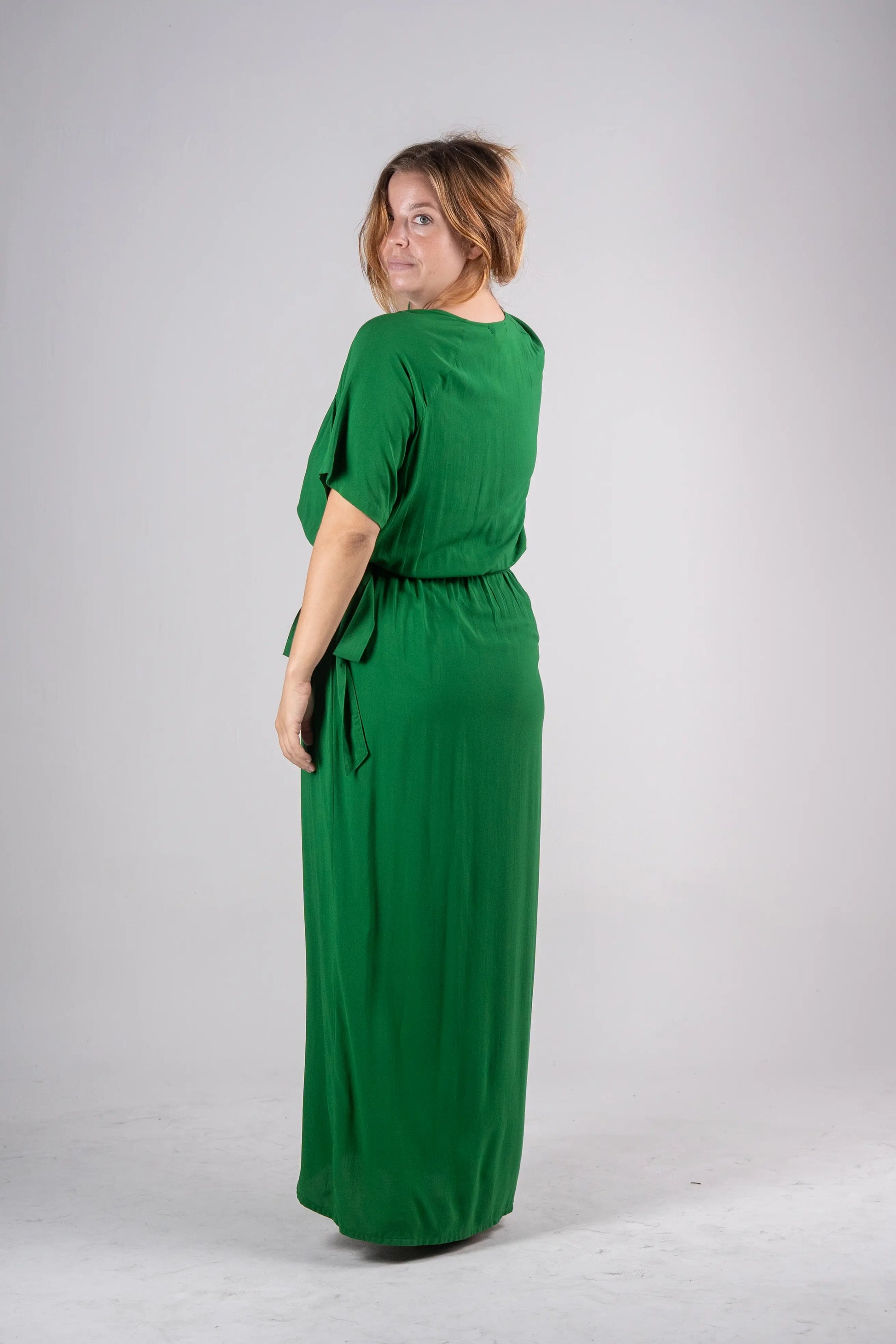 Woman wearing a green dress against a plain background