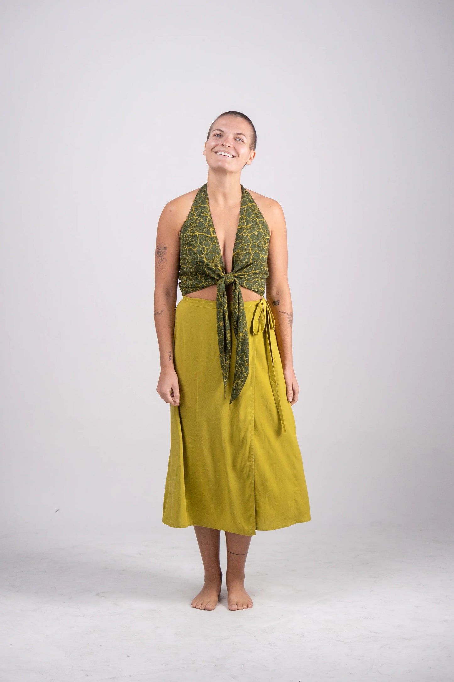 Woman wearing a green patterned top and yellow skirt on a white background
