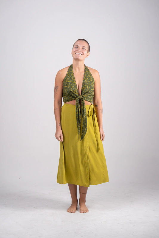 Woman wearing a green patterned top and yellow skirt on a white background