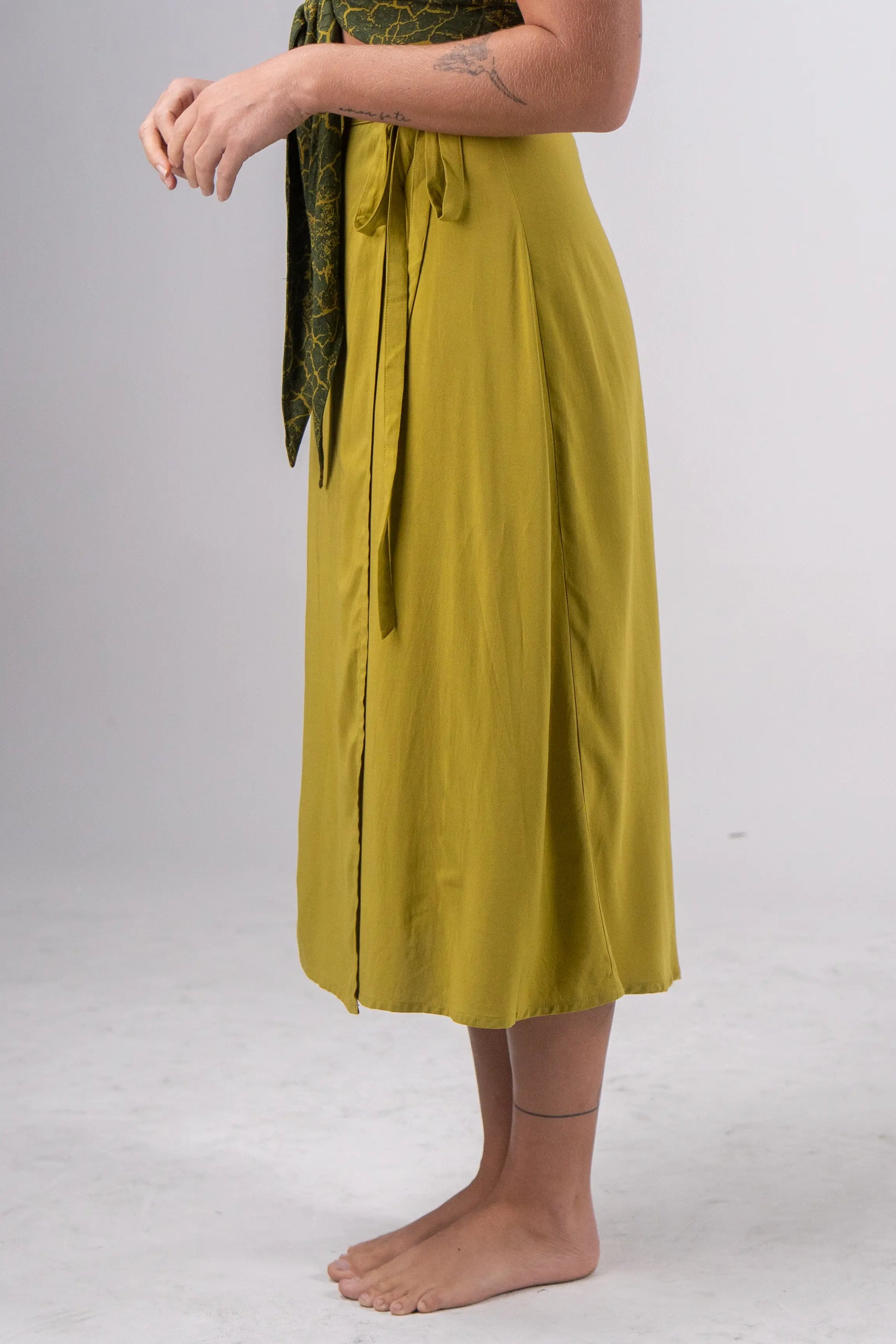 Person wearing a green skirt on a plain background