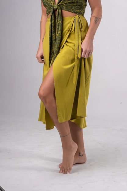 Person wearing a green skirt with a green patterned top on a white background