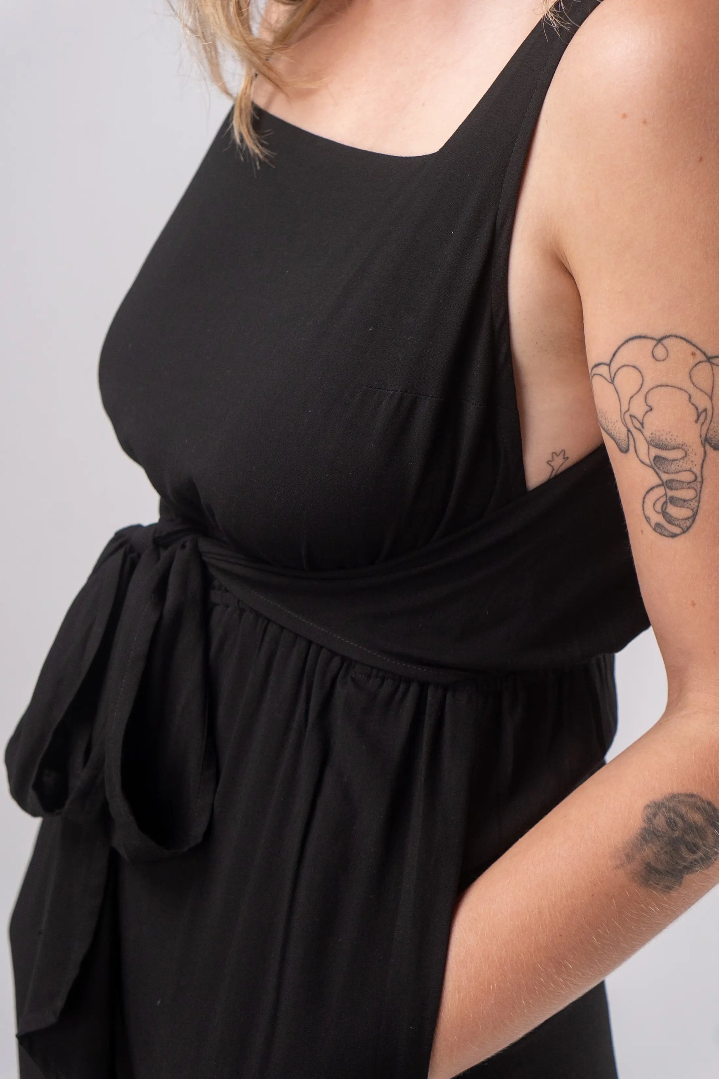 Black sleeveless top worn by a person on a plain background