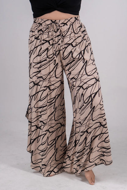 Beige wide-leg pants with black abstract pattern worn by a person on a light gray background