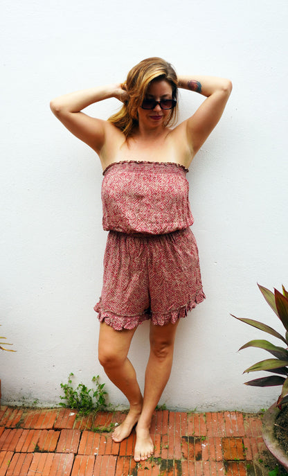 Woman wearing a strapless floral romper against a white wall.