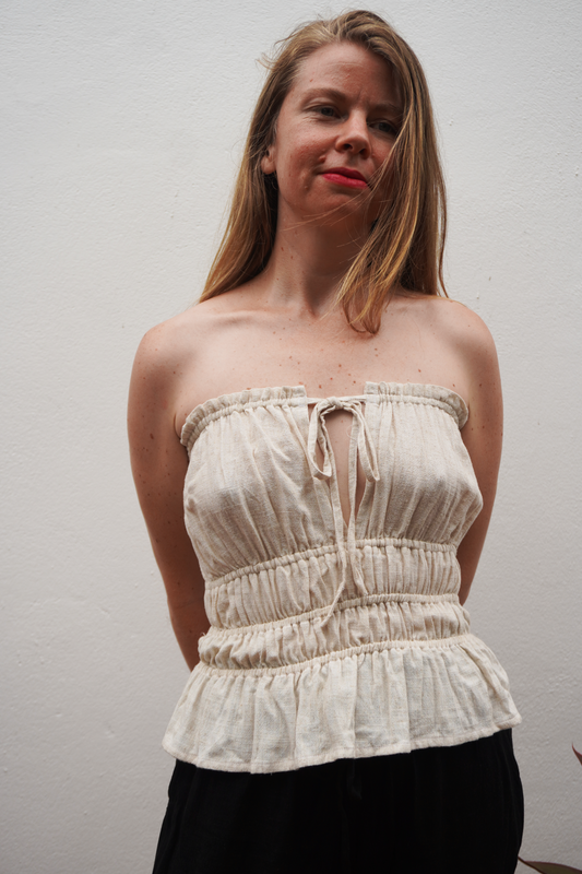 Woman wearing a white strapless top against a plain background