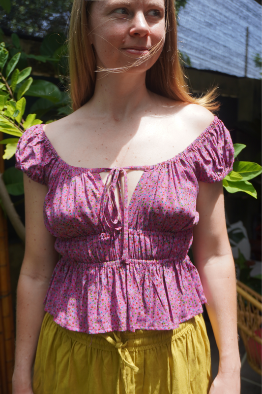 Woman wearing a purple floral top and yellow skirt outdoors
