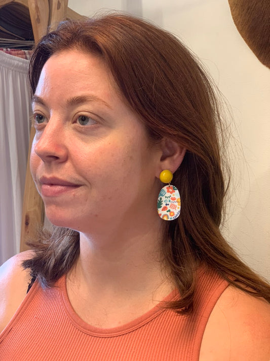 woman wearing earrings with colorful fun design and yellow detail. 