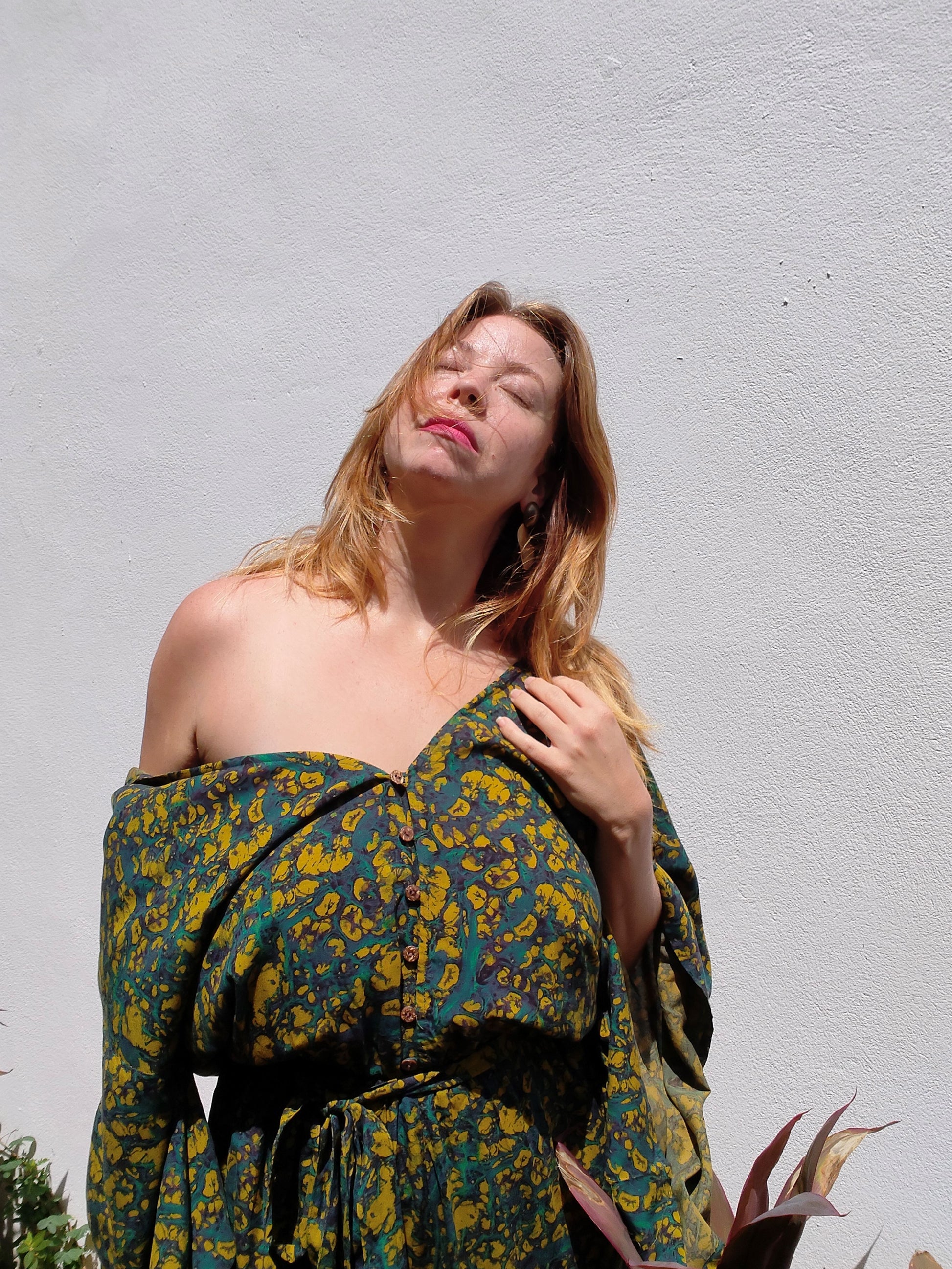 Woman wearing a floral jumpsuit against a plain background