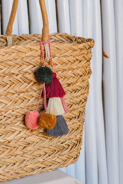 Woven basket with colorful tassels against a light curtain background